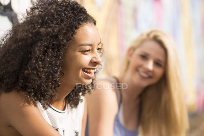 Teenagers relaxing against wall with graffiti — Stock Photo