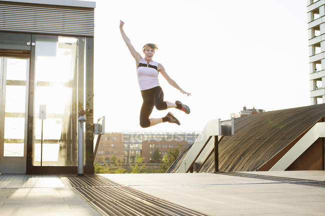 Женщина тренируется, прыгает в воздухе по пешеходному мосту — стоковое фото