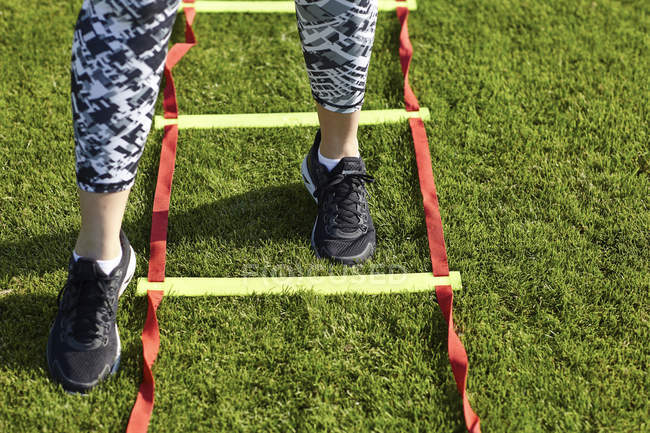 Feet of young woman training on agility ladder — Stock Photo
