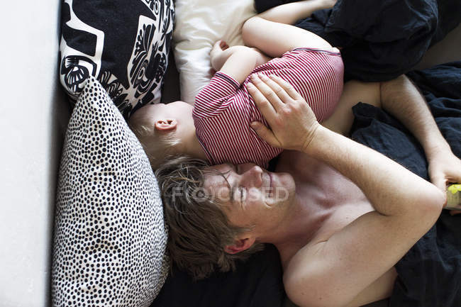 Vater und kleine Tochter liegen zusammen im Bett, Blick über den Kopf — Stockfoto