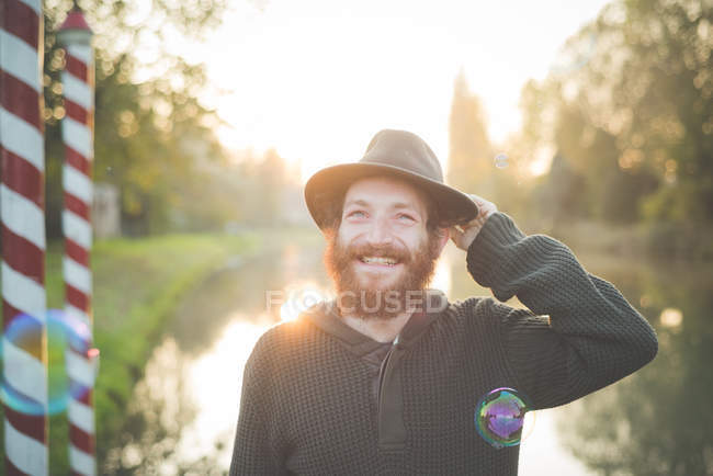 Jeune homme portant un chapeau, souriant — Photo de stock