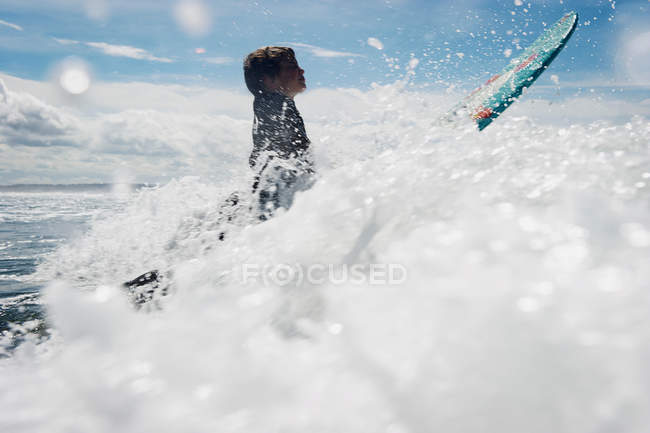 Jeune garçon surfant à travers les vagues — Photo de stock