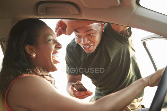 Jovem de pé na porta do carro aberto sorrindo para a jovem mulher — Fotografia de Stock