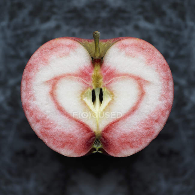 Manzana simétrica mitad con mancha en forma de corazón rojo - foto de stock