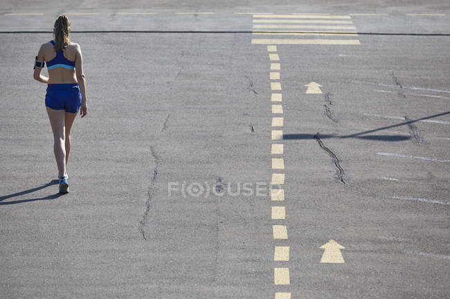 Вид ззаду молодої жінки біжить на парковці — стокове фото
