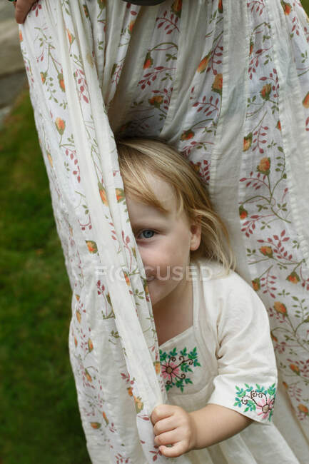 Маленькая девочка прячется за занавесками — стоковое фото