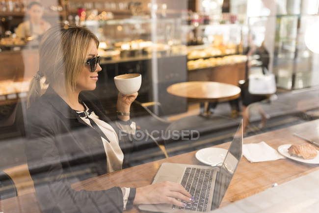 Бізнес-леді, що працює на ноутбуці в кафе — стокове фото