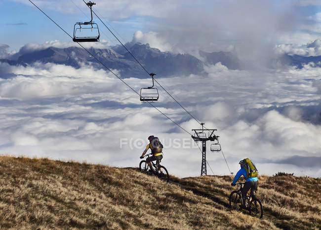 Dois ciclistas de montanha sob teleféricos, Valais, Suíça — Fotografia de Stock