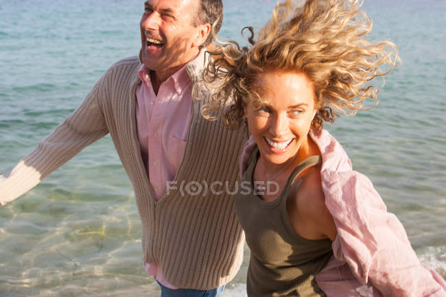 Joyeux couple d'âge mûr qui court au bord de la mer, Majorque, Espagne — Photo de stock