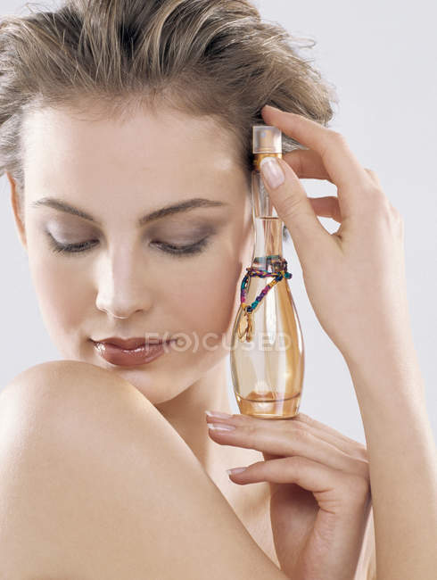 Portrait of young woman with parfume against light background — Stock Photo
