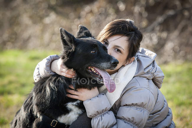 Retrato de una mujer adulta besando a su perro en el campo - foto de stock