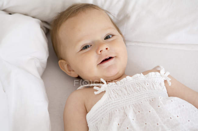Bebê menina deitada e olhando para a câmera — Fotografia de Stock