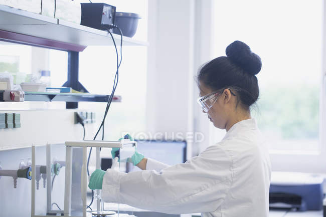 Jovem cientista em laboratório usando equipamentos científicos — Fotografia de Stock