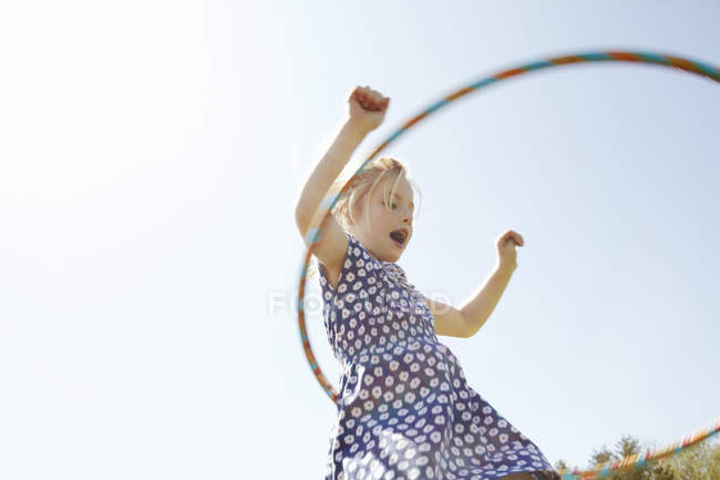Vista de ángulo bajo de la niña jugando con aro de plástico - foto de stock