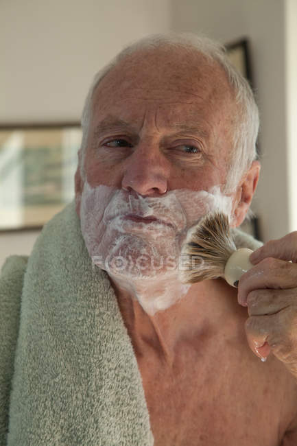 Senior man using shaving brush — Stock Photo