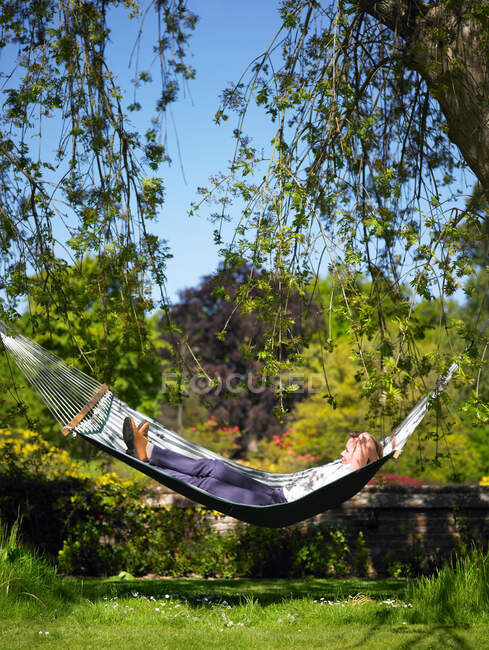 Mujer descansando en hamaca en el jardín - foto de stock