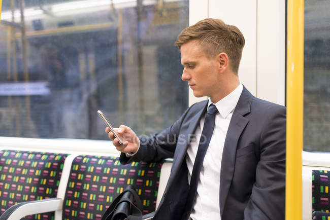Empresario de mensajes de texto en el tubo, metro de Londres, Reino Unido - foto de stock