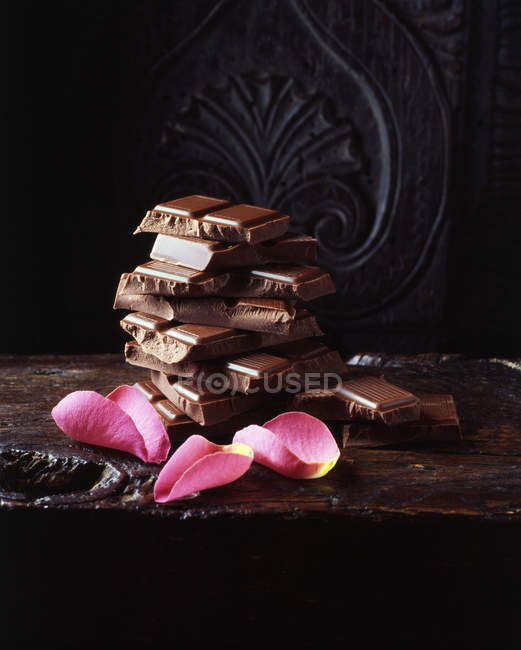 Pink rose petals and broken chocolate bars — Stock Photo