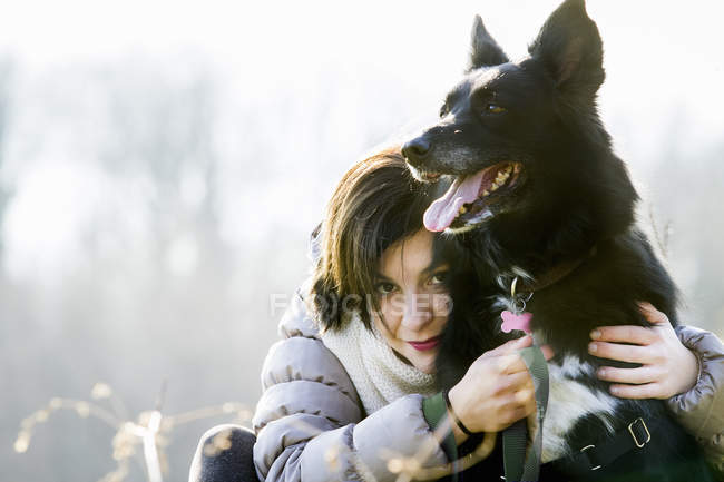 Portrait of mid adult woman hugging her dog — Stock Photo