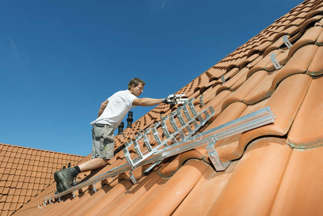 Worker installing framework for solar roof panels on house, Netherlands — Stock Photo