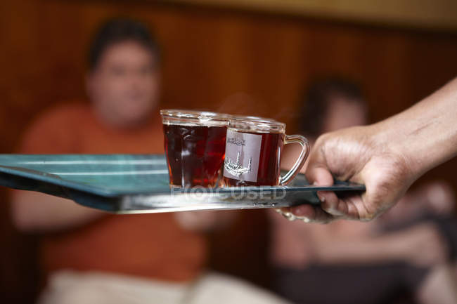 Hand mit Tablett mit Tassen Morgentee im Café, Muskat, Oman, Naher Osten — Stockfoto