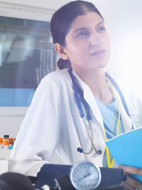 Doctora contemplando notas médicas en el hospital - foto de stock