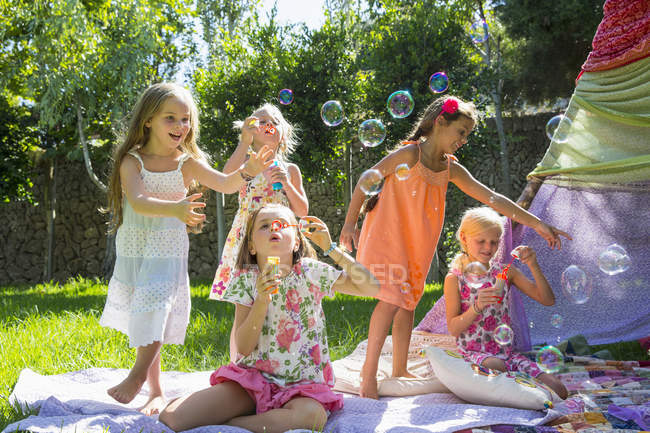 Girls blowing bubbles in summer garden party — Stock Photo