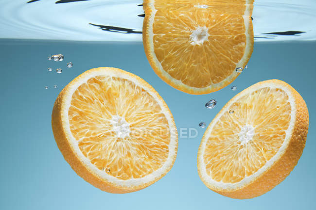 Rodajas de naranja fresca bajo el agua - foto de stock