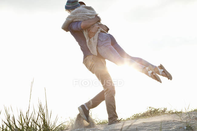 Junges pärchen, das sich am Strand umarmt, dorset, uk — Stockfoto