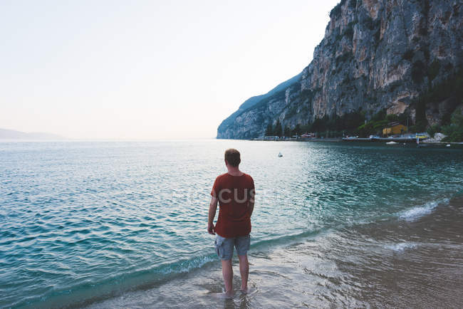 Вид сзади человека, наслаждающегося видом на озеро Гарда, Италия — стоковое фото