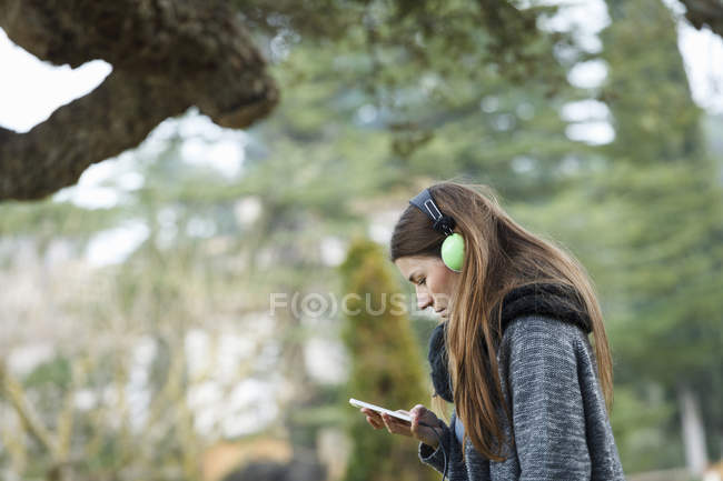 Молодая женщина использует mp3 в лесу — стоковое фото