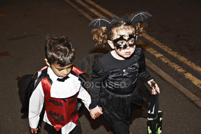 Little girl and toddler boy trick or treating at night — Stock Photo