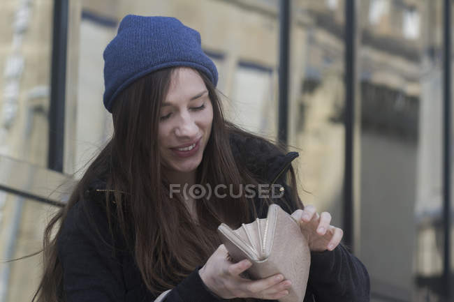 Женщина смотрит на открытую сумочку улыбаясь — стоковое фото