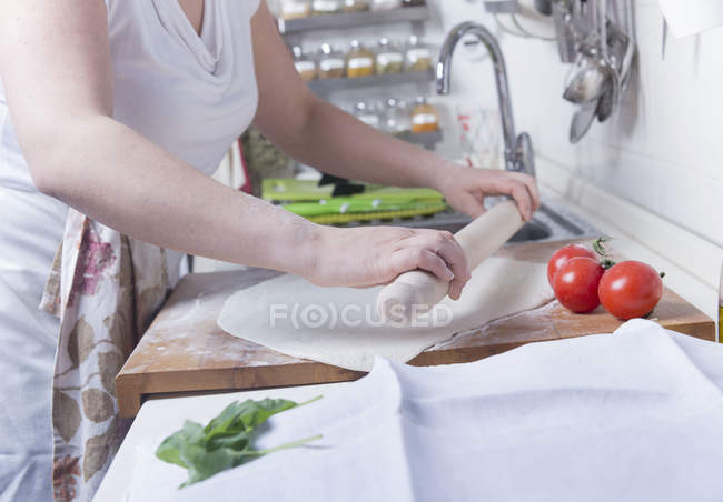 Colpo ritagliato di donna stendere pasticceria sul bancone della cucina — Foto stock
