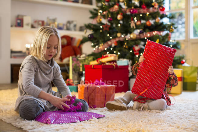 Sorelle che controllano i regali dall'albero di Natale — Foto stock