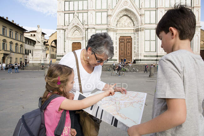 Seniorin und Enkelkinder betrachten Karte auf dem Platz, Florenz, Italien — Stockfoto