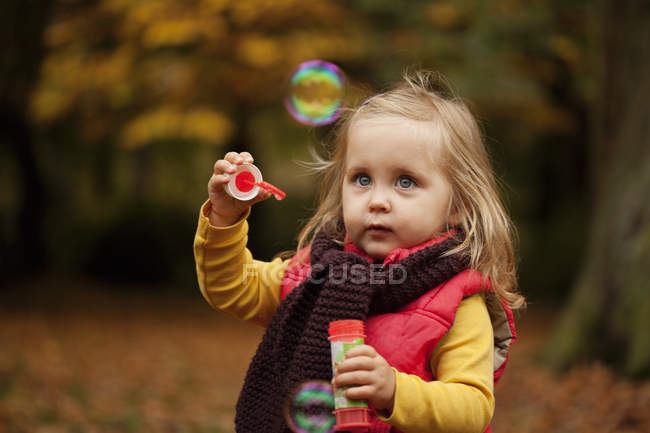 Little girl playing with bubble wand — Stock Photo