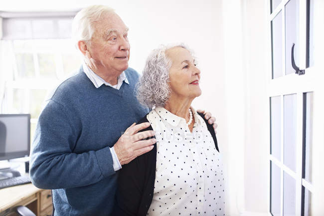 Senior couple in office looking out of window smiling — Stock Photo