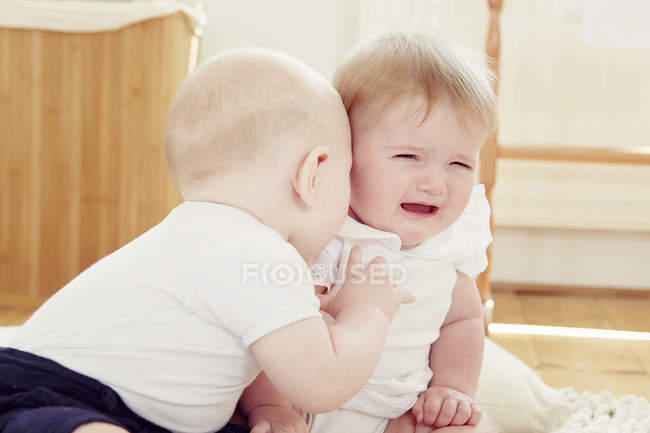 Llorando niña con bebé niño inclinándose hacia - foto de stock