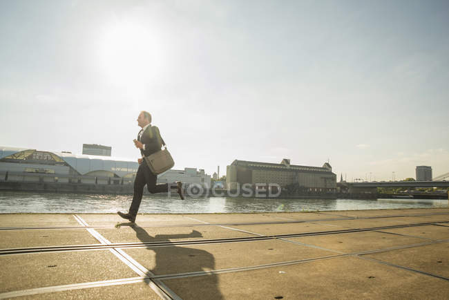 Вид сбоку на бизнесмена, бегущего по набережной — стоковое фото