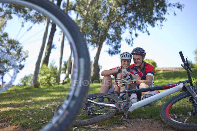 Велогонщики на траве с помощью смартфона — стоковое фото