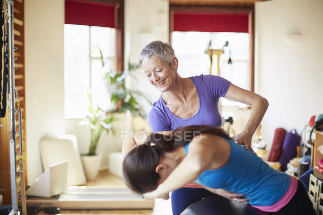 Young female student and tutor using pilates barrel in pilates gym — Stock Photo