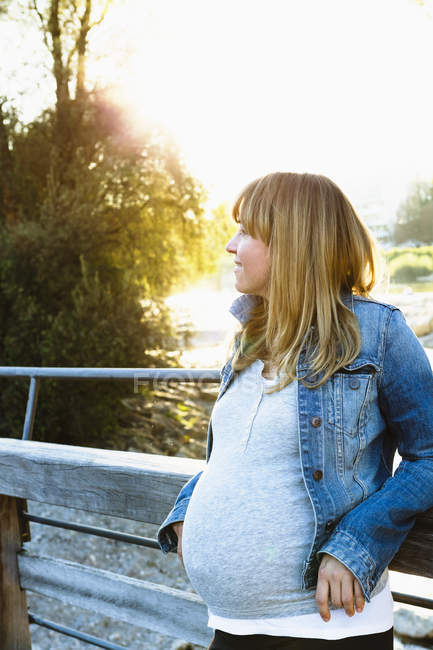 Pregnant woman leaning against railing, looking away — Stock Photo