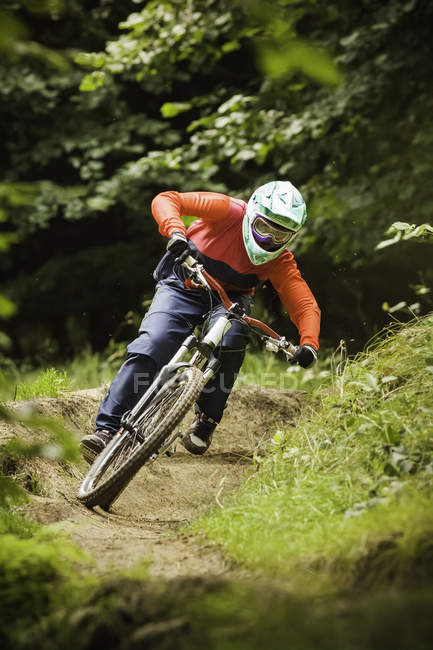 Young woman downhill mountain biking in forest — Stock Photo