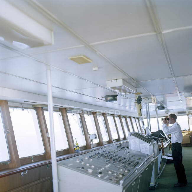 Marinaio che utilizza binocoli sul ponte della nave portacontainer in mare — Foto stock