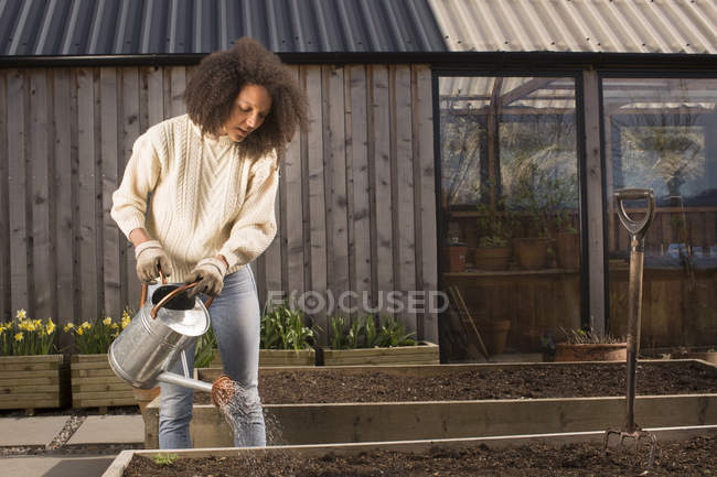 Mid adult woman using watering can — Stock Photo