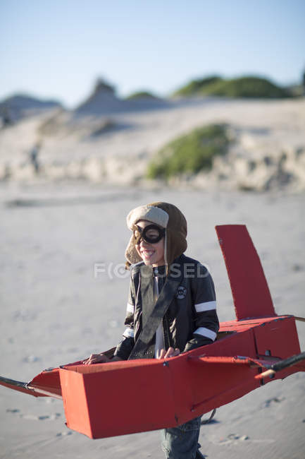 Ragazzo che corre con aeroplano giocattolo in dune di sabbia — Foto stock