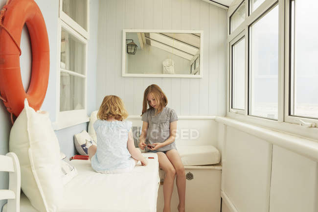 Две сестры играют в карты на крыльце дома отдыха — стоковое фото