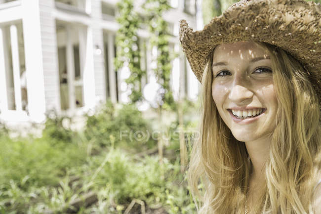 Jeune femme portant un chapeau de paille, portrait — Photo de stock