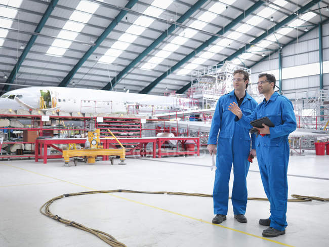 Ingenieros en discusión en fábrica de mantenimiento de aeronaves - foto de stock